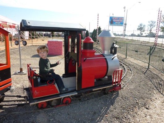 A three-year-old T taking a spin on a train at a local tree lot in Long Beach (CA). This happens to be the same train that is at our local pumpkin patch. The same family also runs a tree lot during the Christmas season and often brings the train back for the kids during the holidays (rides are free with a tree purchase, or $2-ish otherwise).