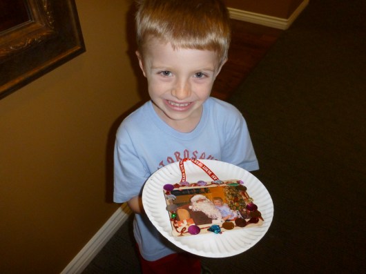 A very jolly and proud T shows off his picture with Santa in the frame he made.