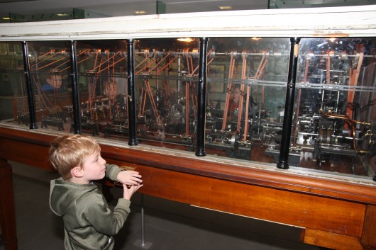 T moving machinery inside a scale-model factory at Science Museum, London.