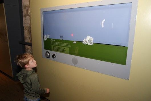 T playing a trajectory-simulation game at the Tower of London inside of White Tower.