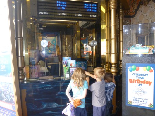 The kids peeking into the box office at the El Capitan Theatre.