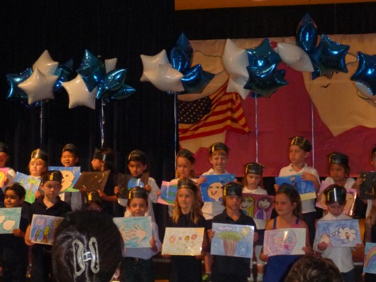 T and other Kindergarteners singing, "What a Wonderful World," holding up illustrated pictures they drew to coordinate with different lines in the song. Sniff.